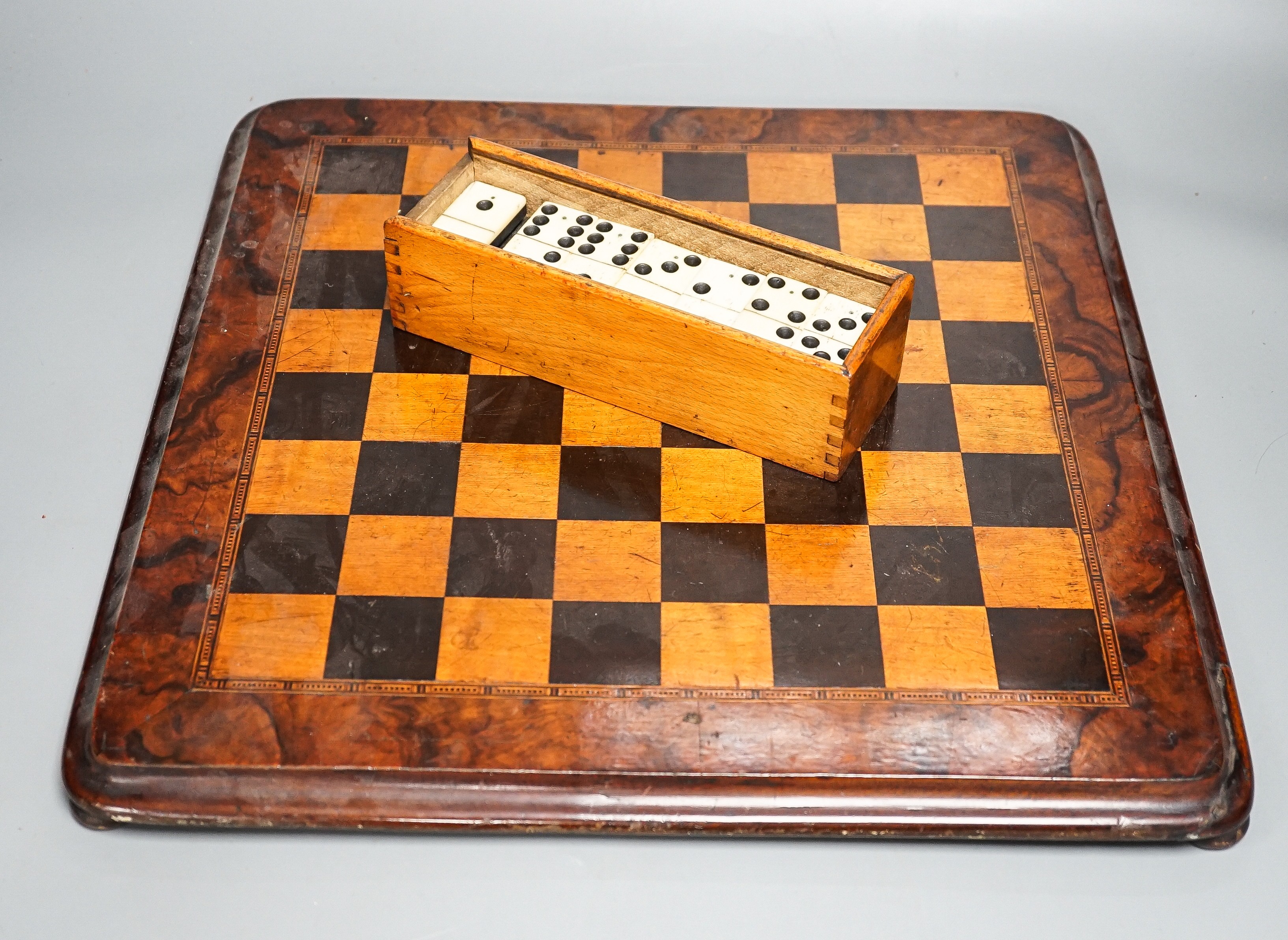 A late 19th century walnut, ebony and sycamore chessboard together with a box set of dominoes, chessboard 41cm x41cm